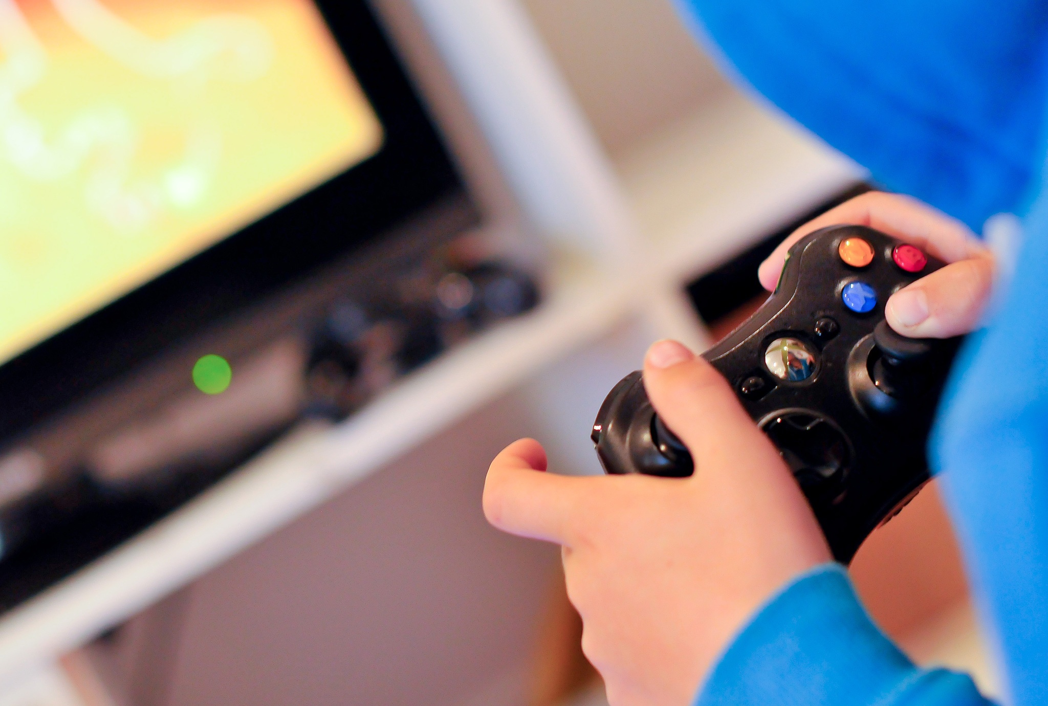 Niño con sudadera azul jugando videojuegos con control remoto en su mano